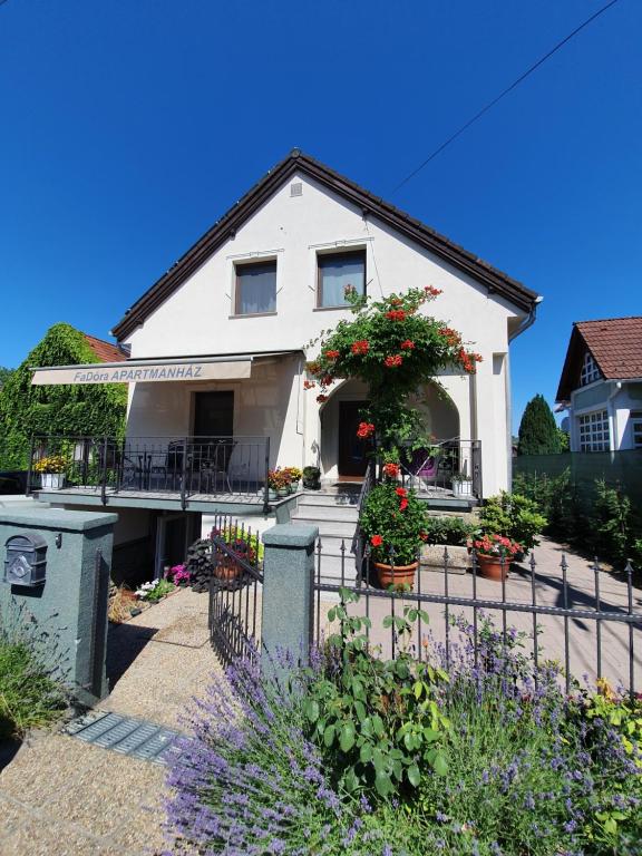 a white house with flowers in the front yard at FaDóra Apartman in Tihany