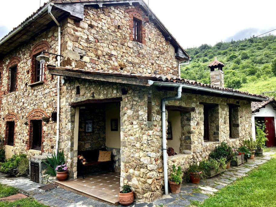 uma casa de pedra com um cão sentado à porta em Casa el Frances em Candamin