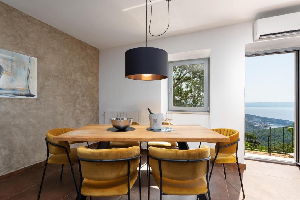 a dining room with a wooden table and yellow chairs at CASA GIUSEPPE Luxury house with an amazing view in Labin