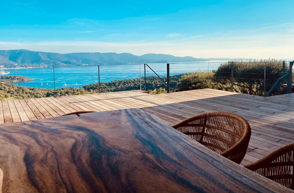 a wooden table on a deck with a view of the ocean at Villa Les Alyzés in Bormes-les-Mimosas
