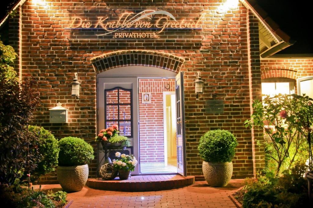 uma porta da frente de um edifício de tijolos com plantas e flores em Landhaus Krabbe von Greetsiel em Greetsiel