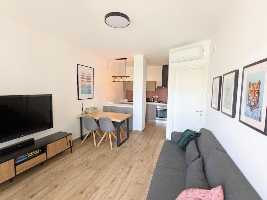 ein Wohnzimmer mit einem Sofa und einem Tisch mit einem TV in der Unterkunft Appartamento nuovissimo con giardino, a due passi dal centro in Sirolo