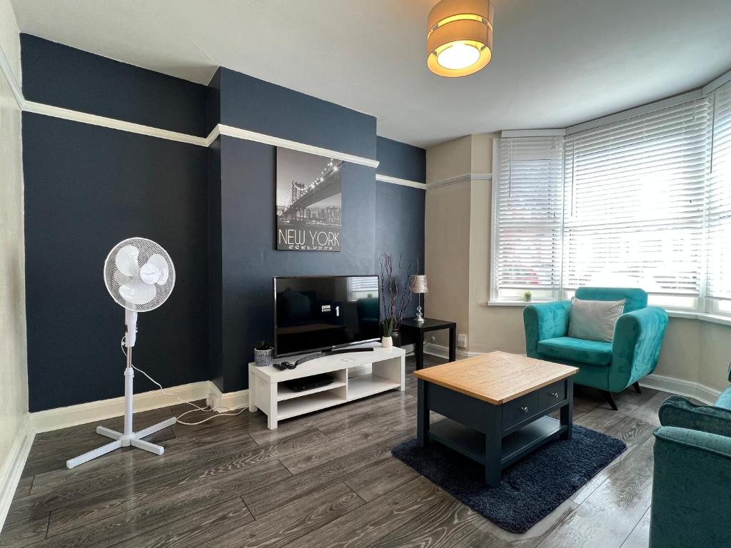 sala de estar con pared de acento azul y ventilador en Comfortable King Bed - Location - Contractors - Family - Parking en Bedford