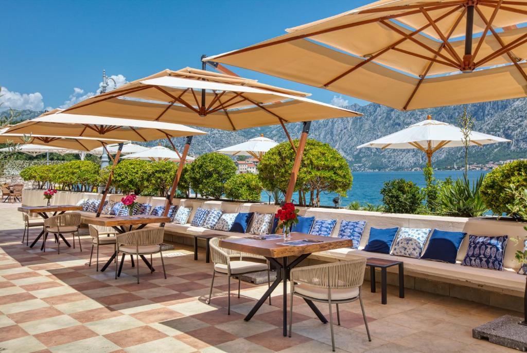 a patio with tables and chairs and umbrellas at Hotel Splendido in Kotor
