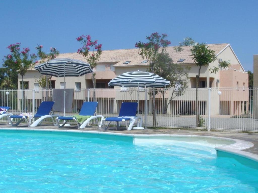una piscina con sillas y sombrillas en Appartement T2 dans résidence avec piscine, en Moriani Plage