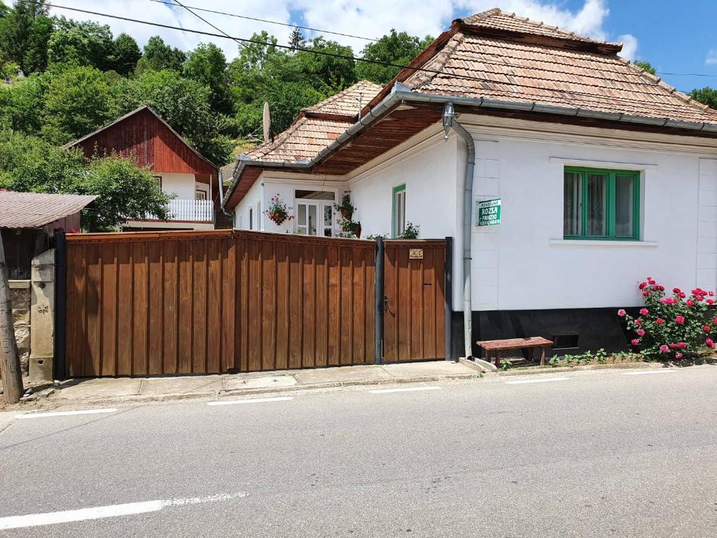 a white house with a wooden fence next to a street at Rózsa Panzió in Rimetea