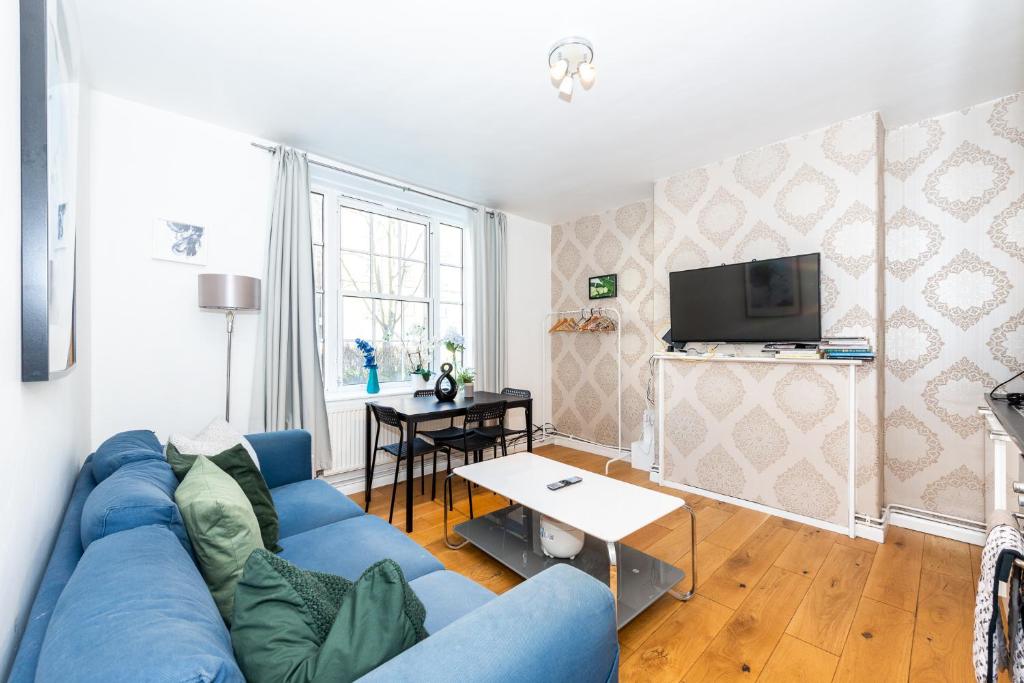 a living room with a blue couch and a tv at Pass the Keys Stay Central in Sunny Waterloo Apartment in London