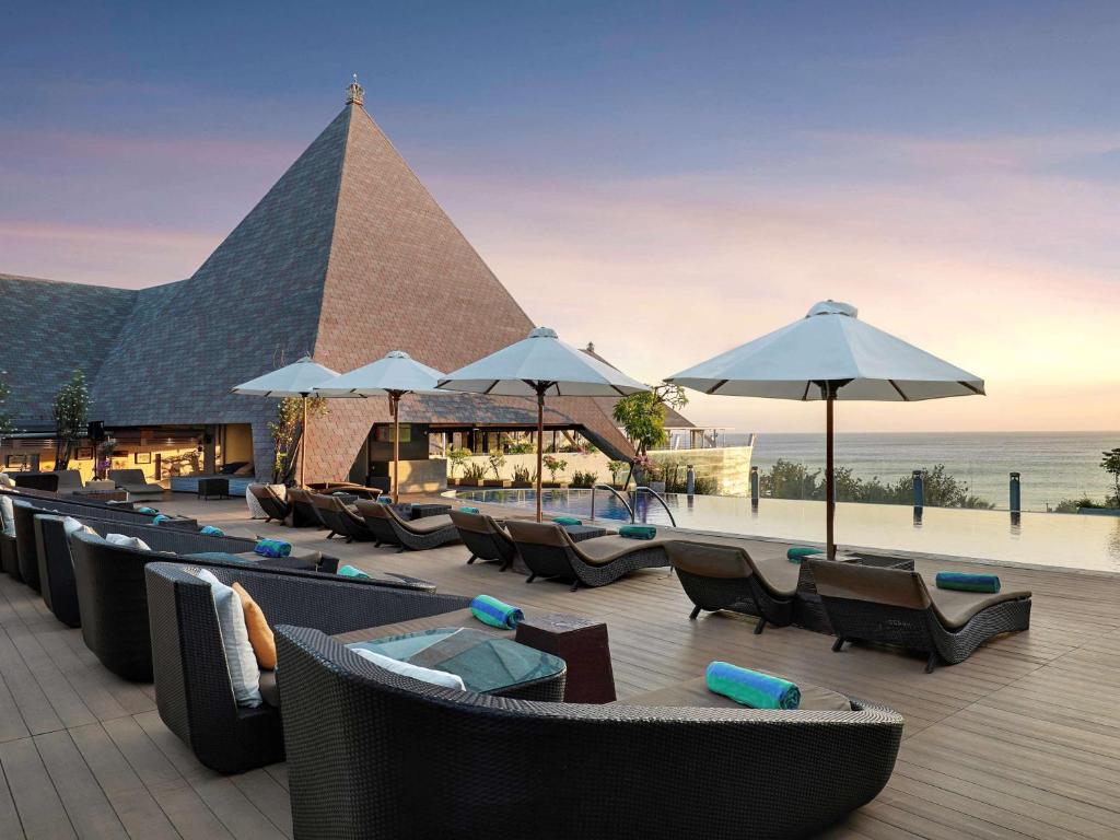 un restaurante con sillas, mesas y sombrillas en The Kuta Beach Heritage Hotel - Managed by Accor, en Kuta