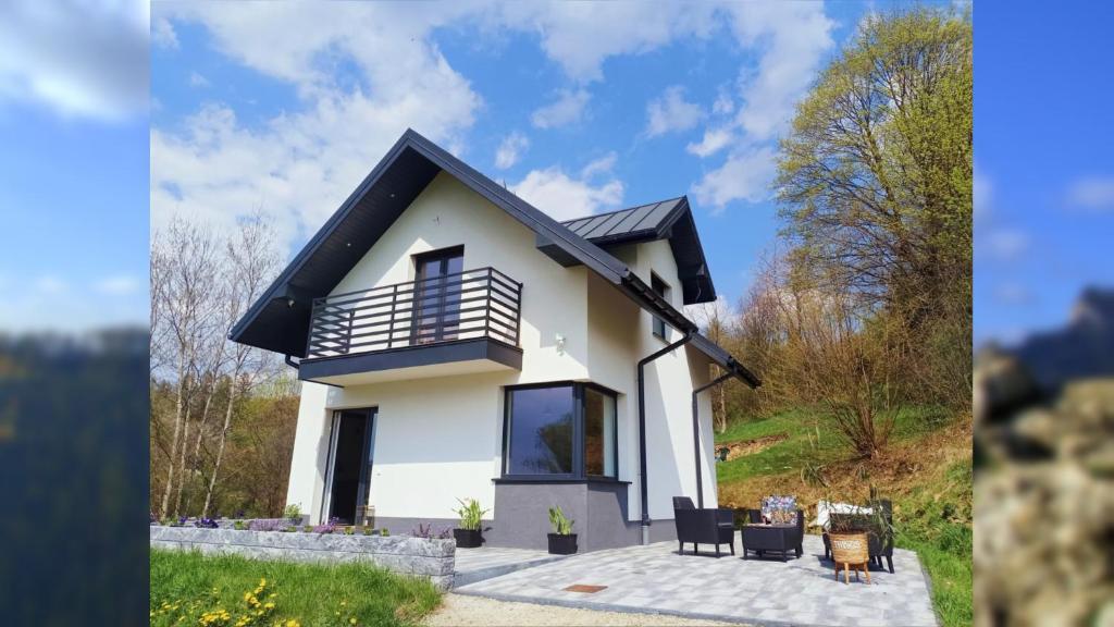 a small white house with a balcony on top at Domek w malowniczych Pieninach in Krościenko