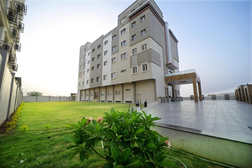 un grand bâtiment avec une cour herbeuse devant lui dans l'établissement The Sky Imperial - Shahi Hotels & Resort, à Nathdwara