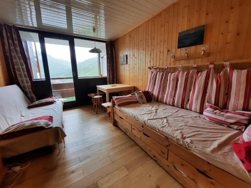 - une chambre avec un canapé dans une pièce dotée de murs en bois dans l'établissement Studio pour 2 personnes avec balcon Sud face au jardin ESF, proche des pistes et remontées mécaniques - FR-1-452-269, aux Menuires