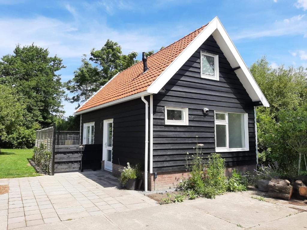 una pequeña casa negra con entrada en Vakantiehuis Boomgaard, en Vrouwenpolder
