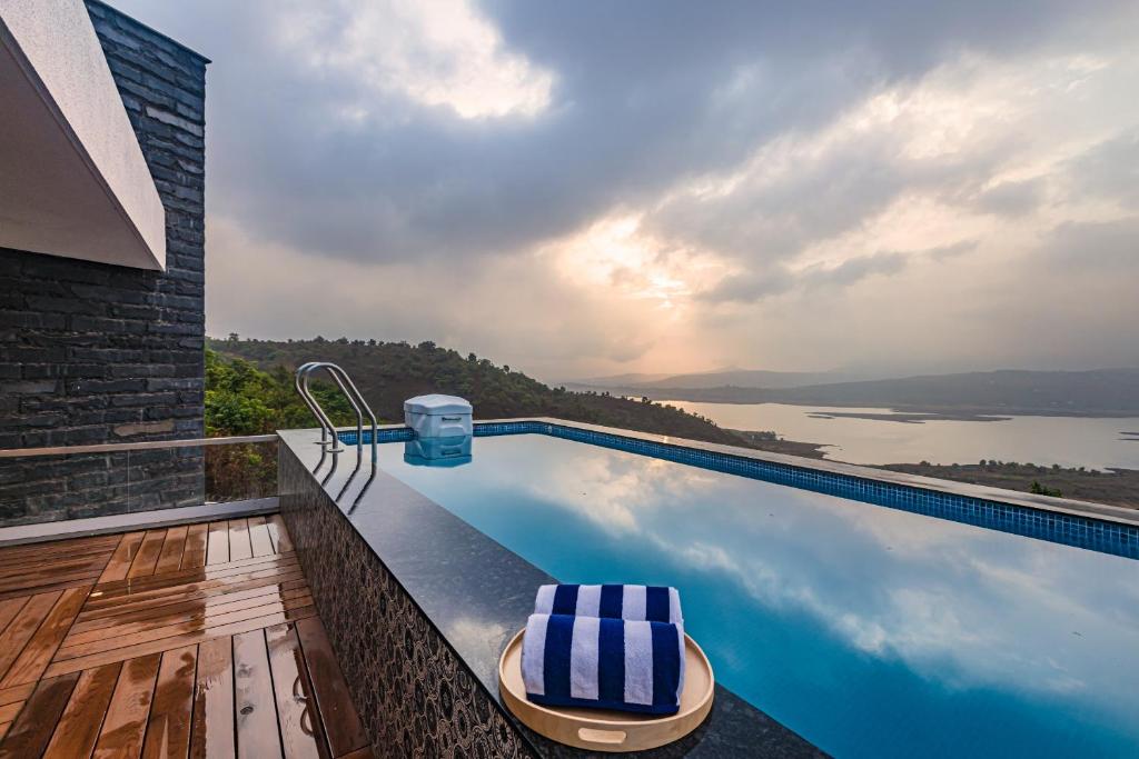 a swimming pool with a view of the water at SaffronStays Kaia Waters by Kosha Villas, Pawna - Greek style villa with panoramic view of Pawna lake in Kolvan
