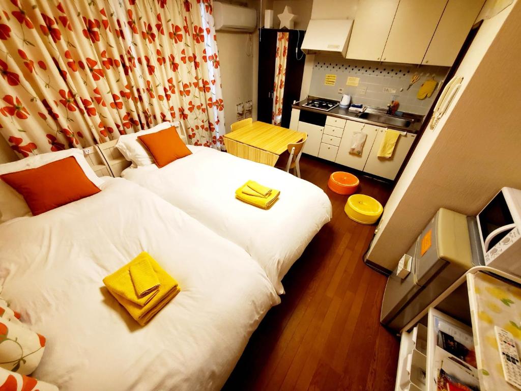 神戸市にあるpetit room201三宮10mimのベッド2台とキッチンが備わる小さな客室です。
