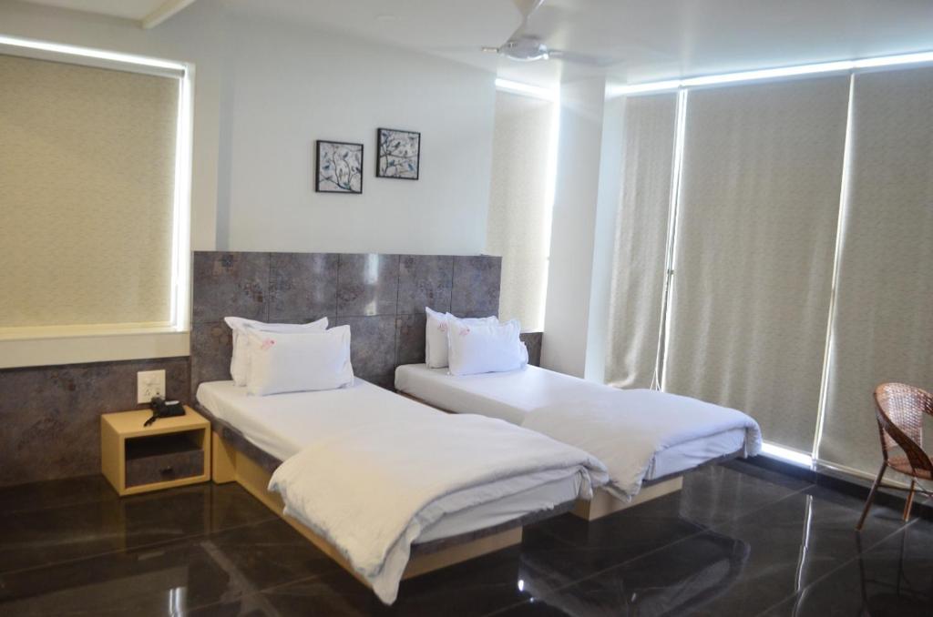 two twin beds in a room with a window at Hotel O2 Sangli in Sangli