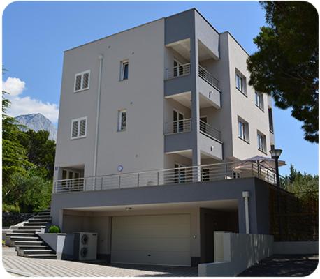 ein großes weißes Gebäude mit einer Treppe davor in der Unterkunft Apartments Leon in Baška Voda