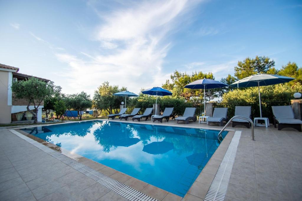 a swimming pool with chairs and umbrellas at Aeolos Zante Villas with Heated Pool in Vasilikos