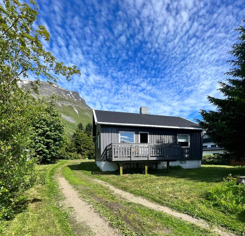 a black house with a balcony on a dirt road at Lyngen House in Olderdalen