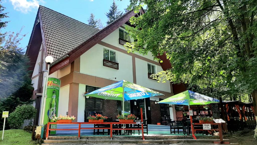 two tables with umbrellas in front of a building at Pensiunea Happy Inn in Vatra Dornei