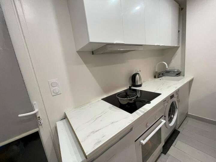 een witte keuken met een wastafel en een wasmachine bij maisonnette de 21m2 plus terrasse in Gentilly
