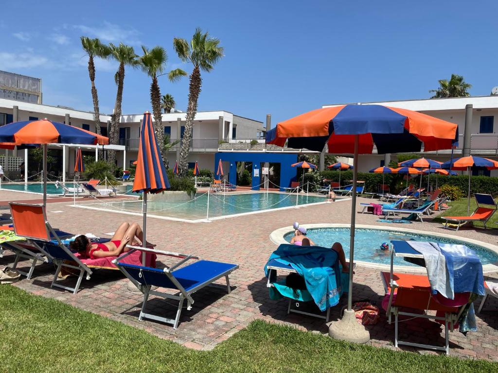 a woman laying in lawn chairs next to a swimming pool at SALENTO - Casa vacanza - Torre dell’orso in Torre dell'Orso