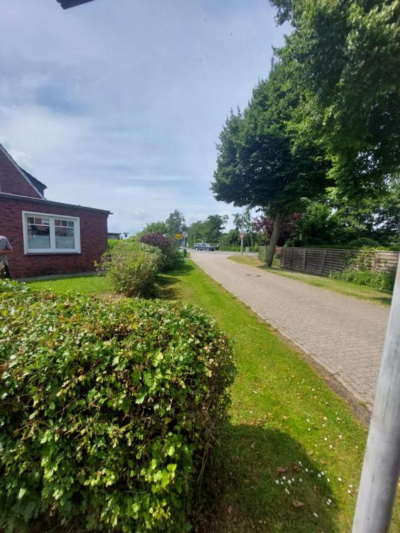 una casa con un seto al lado de una calle en Meeresleuchten, en Krummhörn