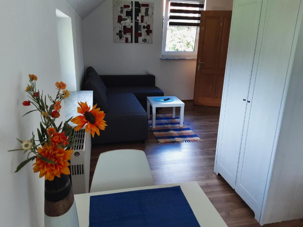 a living room with a couch and a vase of flowers at Apartment-Ferienwohnung 3 Treffen am Ossiachersee in Treffen