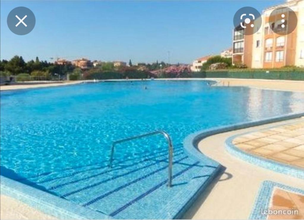 a large swimming pool with blue water in a building at appartement au LAGON BLEU à Fréjus, garage, tennis & piscine 1200 M2 in Fréjus