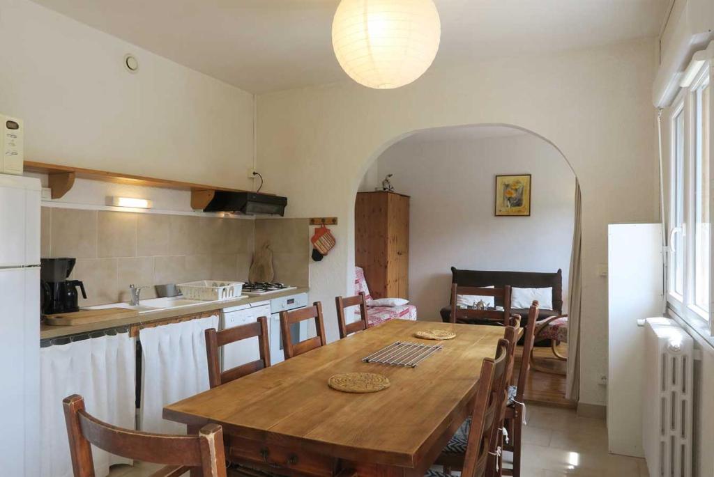 une cuisine avec une table en bois et une table et des chaises dans l'établissement Gîte CARLINES - 6 personnes - 