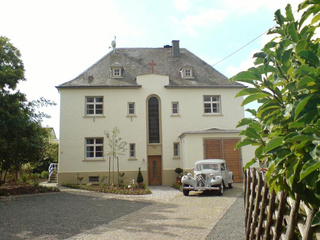 een oude auto geparkeerd voor een wit huis bij Apartment Altes Pfarrhaus in Köwerich