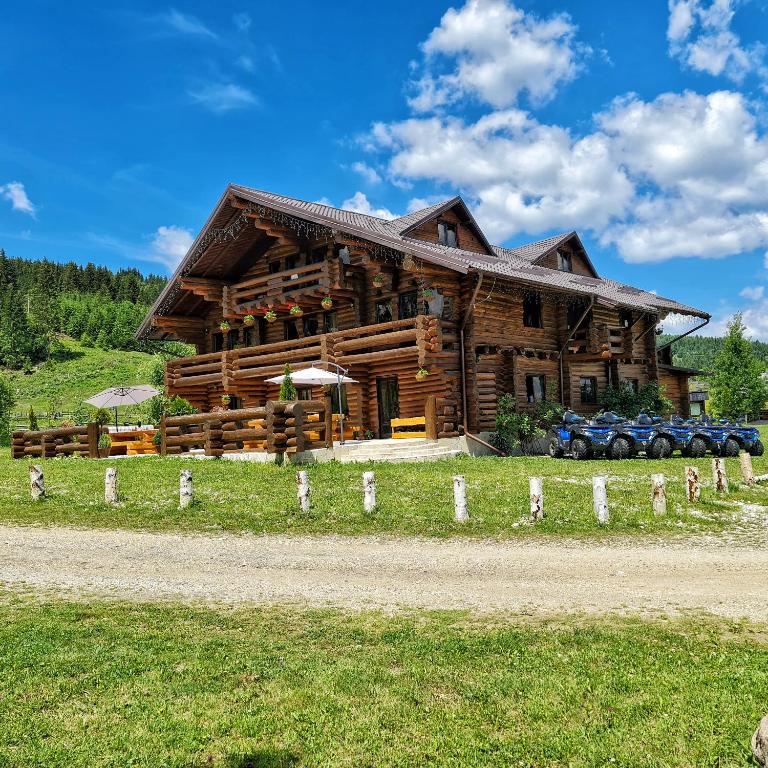 a log cabin with cars parked in front of it at Pensiunea Agroturistica Casa Brazilor in Sărişoru Mare