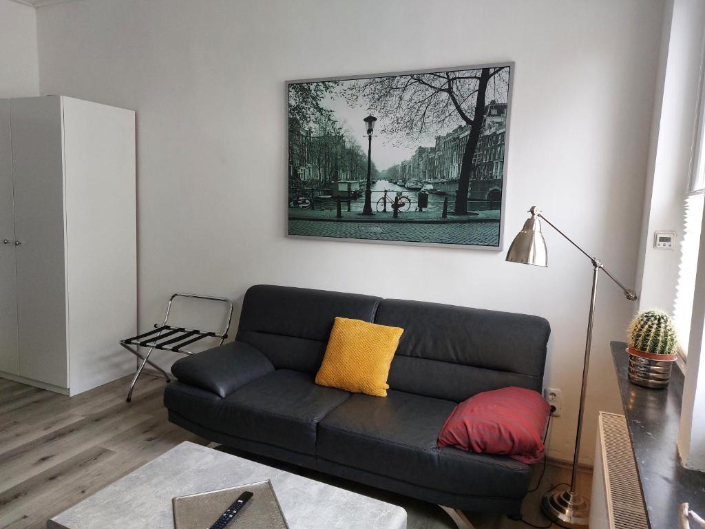 un salon avec un canapé noir et une photo sur le mur dans l'établissement City Apartment in Velbert-Mitte, à Velbert