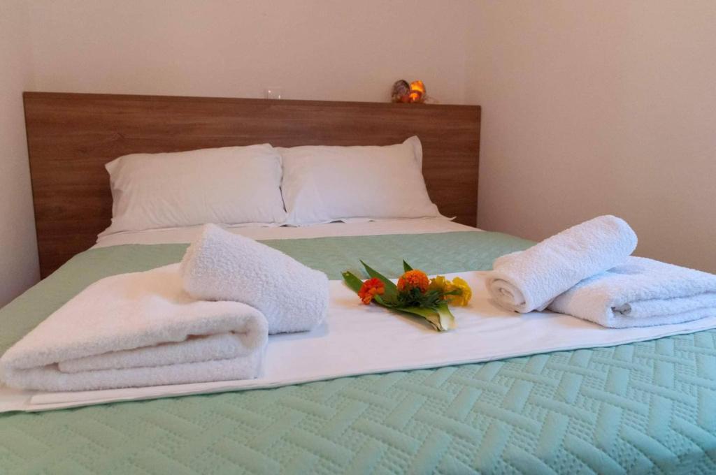 ein Bett mit Handtüchern und Blumen darauf in der Unterkunft Charoula's Apartments in Syvota