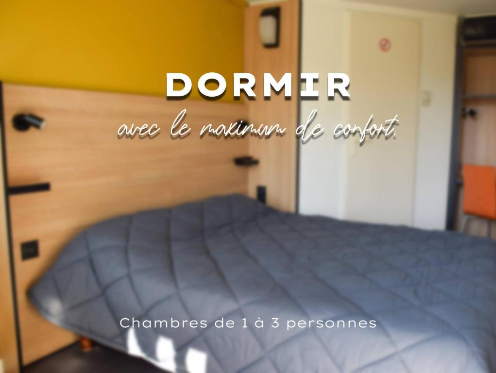 a bed in a bedroom with the words denerrica be mountains bequeat at Premiere Classe Rodez in Rodez