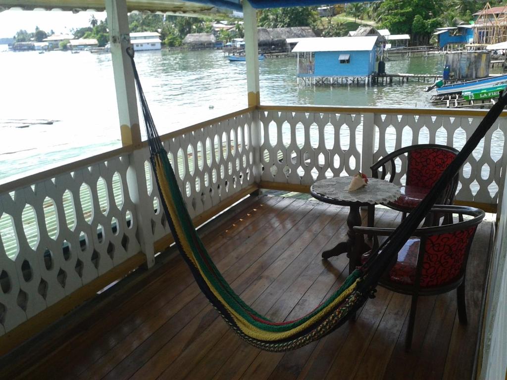 a hammock and a table on a porch with the water at Hotel Caribbean View in Bastimentos