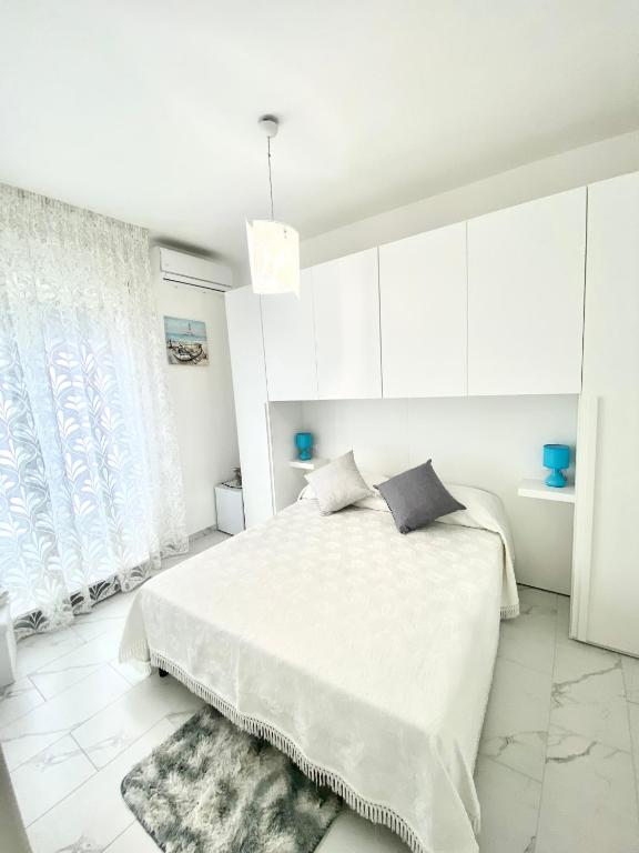 a white bedroom with a bed and white cabinets at Casa Tortora in Santa Maria di Castellabate