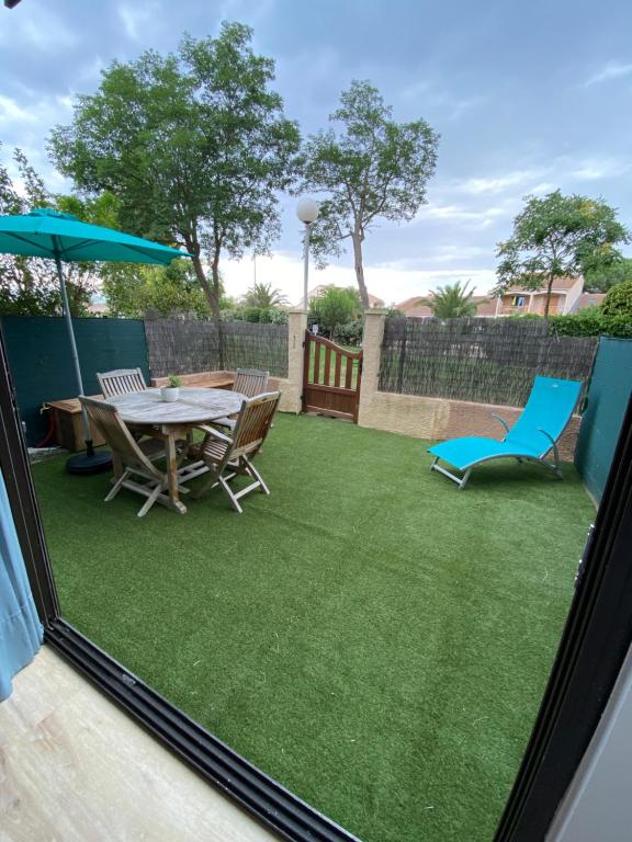 un patio avec une table, des chaises et un parasol dans l'établissement Studio Saint cyprien Plage, à Saint-Cyprien
