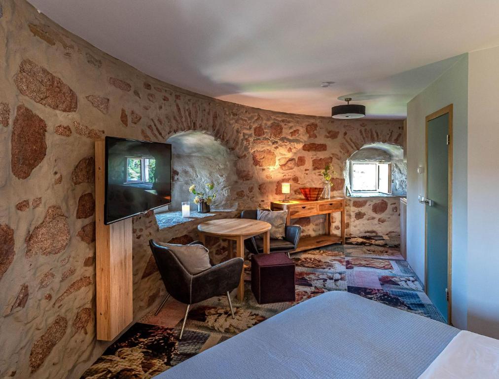 a bedroom with a stone wall with a tv and a table at Muehlbastei-Bautzen-Turmzimmer-2 in Bautzen