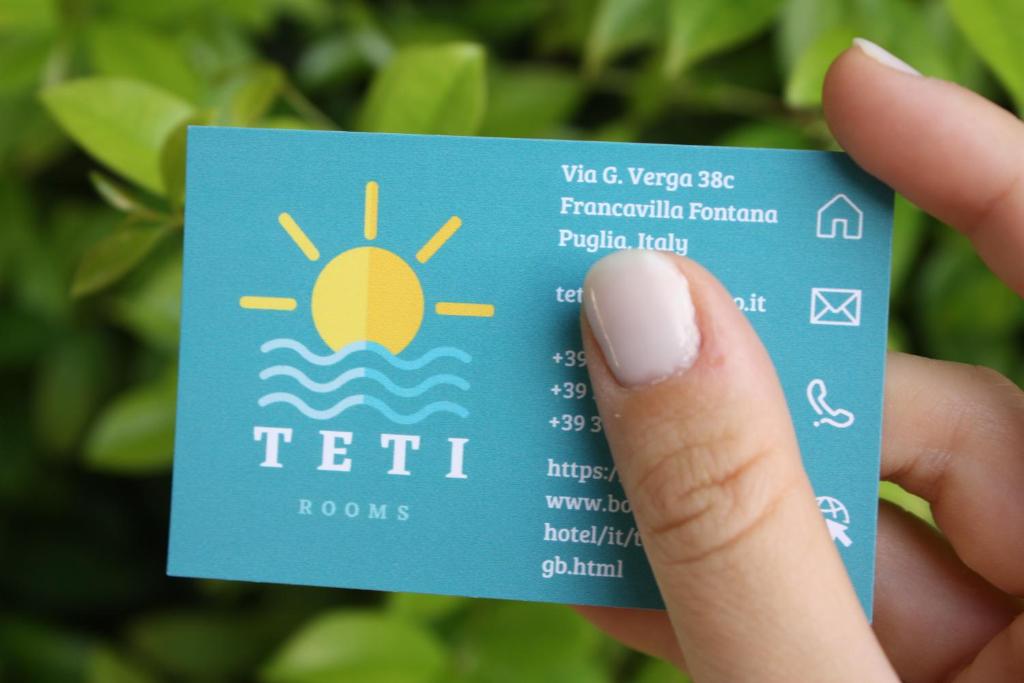 a hand holding a blue card with a picture of the sun at TETI Rooms in Francavilla Fontana