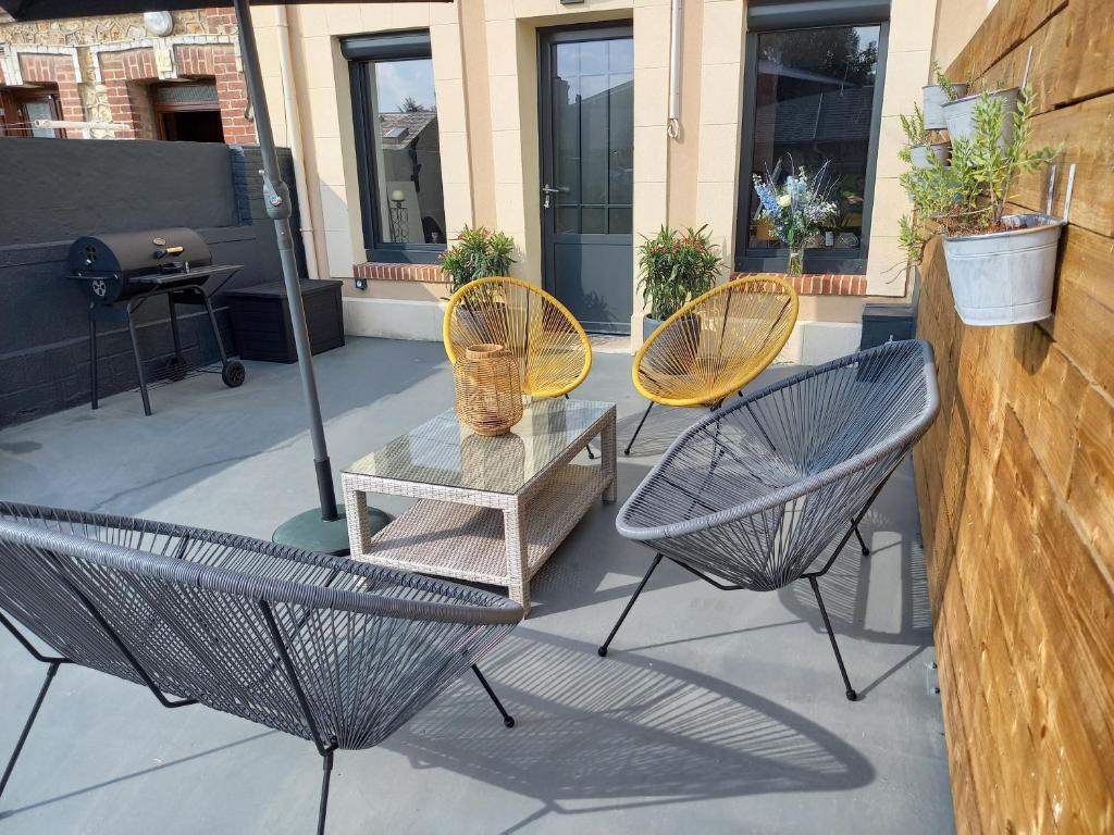 een patio met 3 stoelen, een tafel en een muur bij Gîte 8 places à Fécamp La Bonne Escale in Fécamp