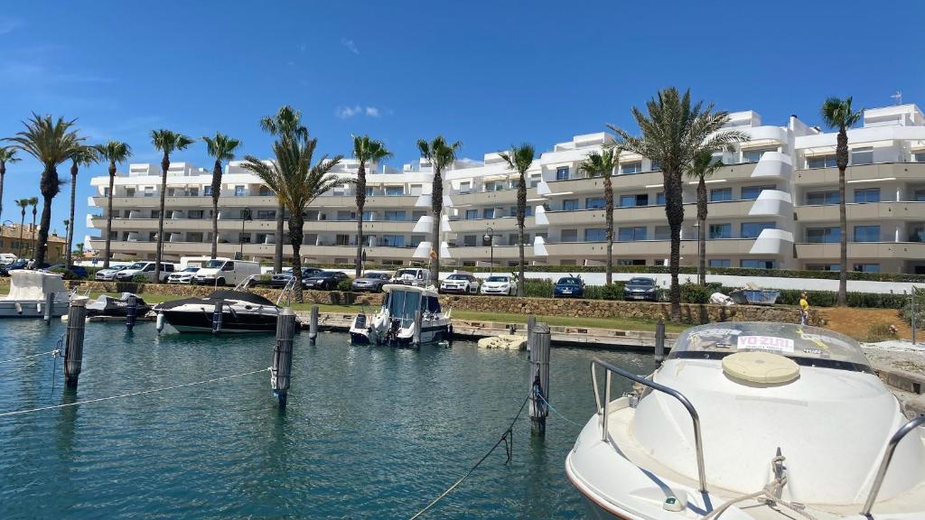 un barco atracado en un puerto deportivo frente a un gran edificio en La Marina Sotogrande Pier2, en Torreguadiaro