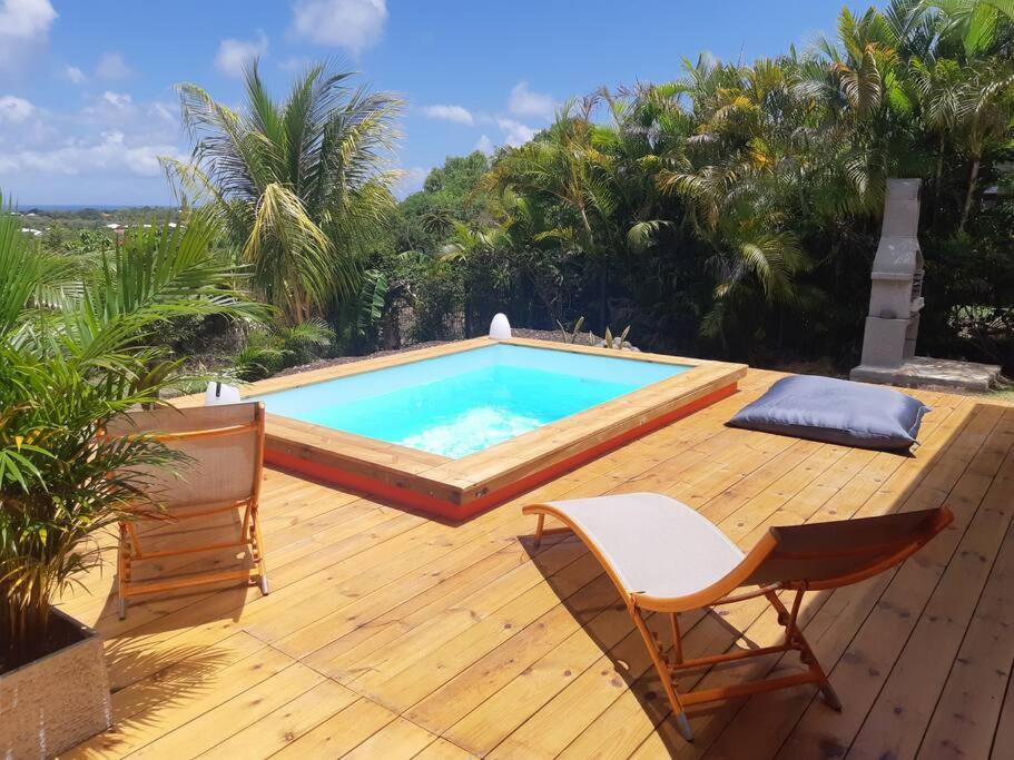 een zwembad op een houten terras met twee stoelen bij TI COIN RELAX bungalow vue mer piscine privée in Saint-François