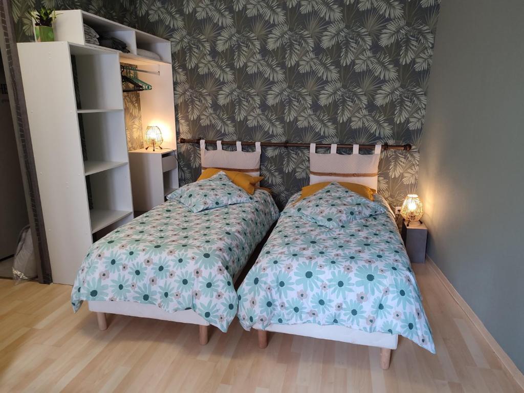 dos camas sentadas una al lado de la otra en un dormitorio en Studio indépendant accès direct autonome. en Le Cateau