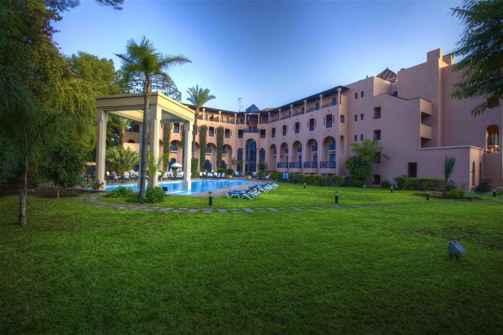 
a large building with a large lawn in front of it at Hotel Marrakech le Tichka in Marrakesh
