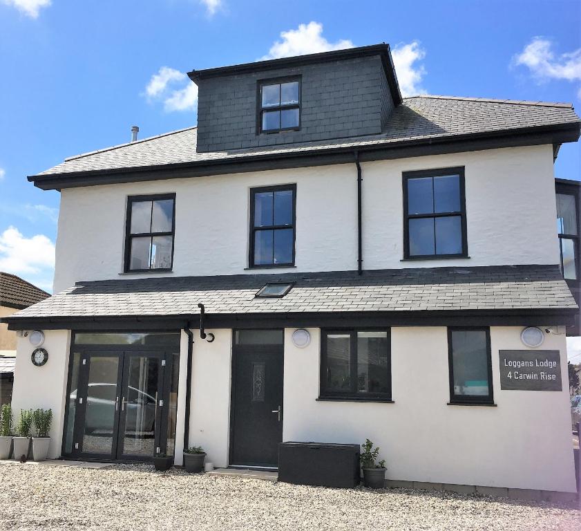 a white house with black windows and doors at Loggans Lodge in Hayle