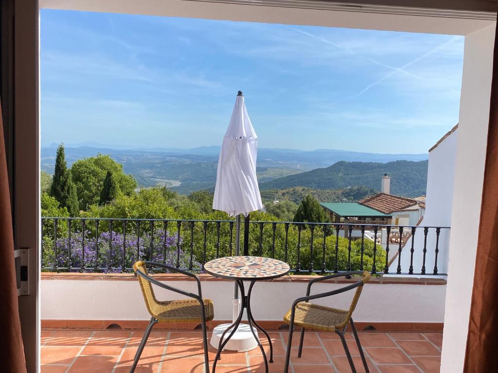 balcón con mesa, sillas y sombrilla en Villa Laguneta en Gaucín