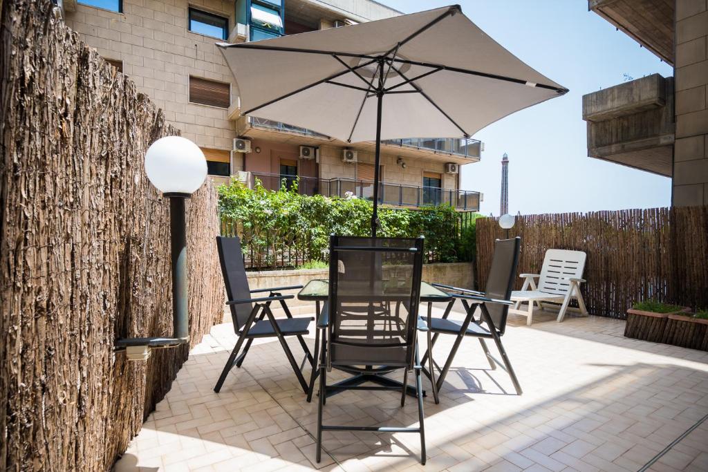einen Tisch und Stühle mit Sonnenschirm auf einer Terrasse in der Unterkunft La terrazza sull'Africa in Catania