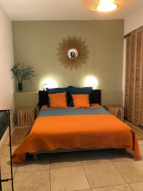 a bedroom with a large bed with an orange blanket at Sous le Clocher in Marseille