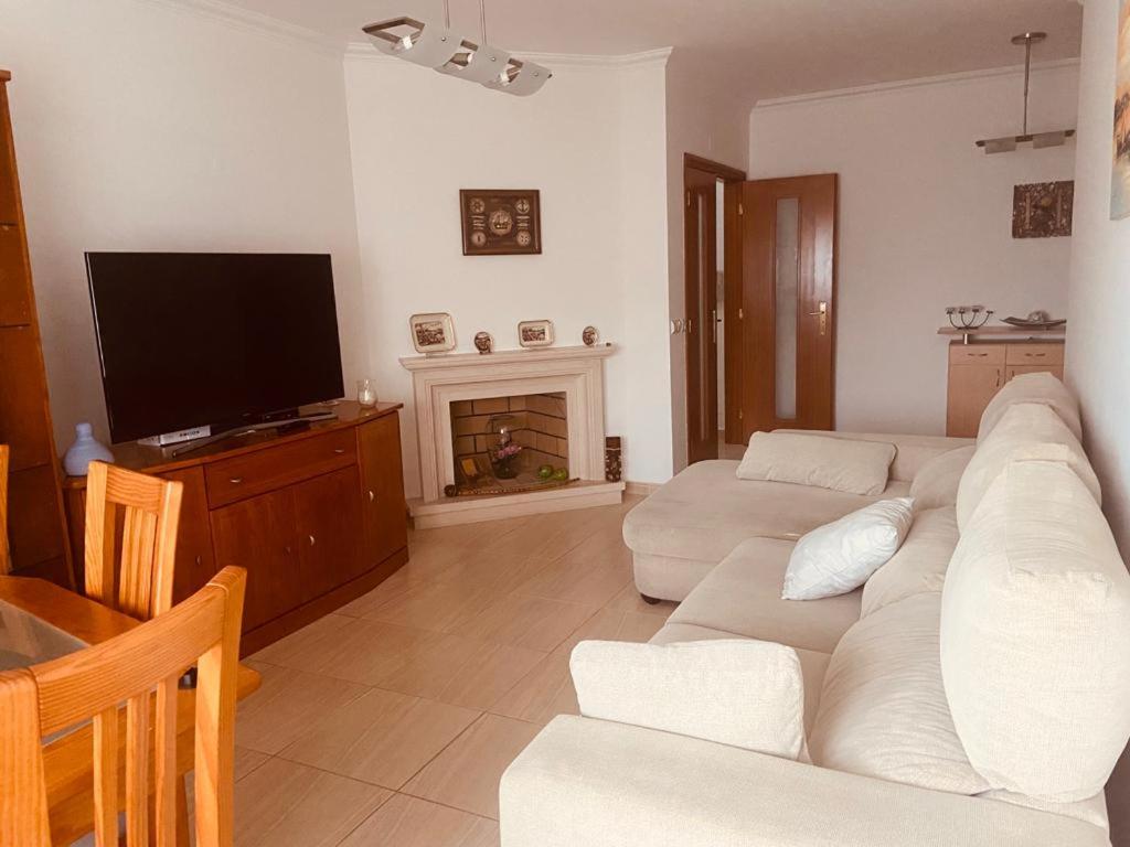 ein Wohnzimmer mit einem weißen Sofa und einem TV in der Unterkunft Casa da Concha in Nazaré