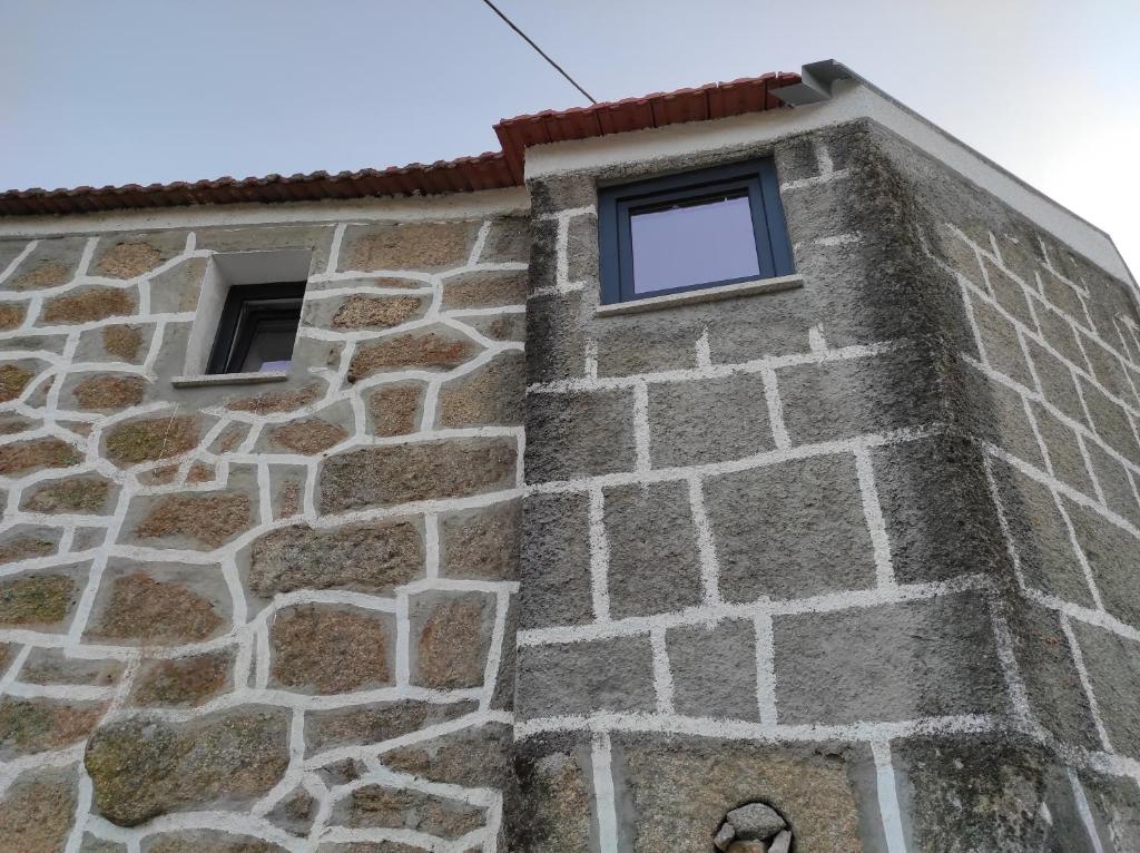 un edificio de piedra con dos ventanas. en Casa Penedo do Raposo, en Muxagata